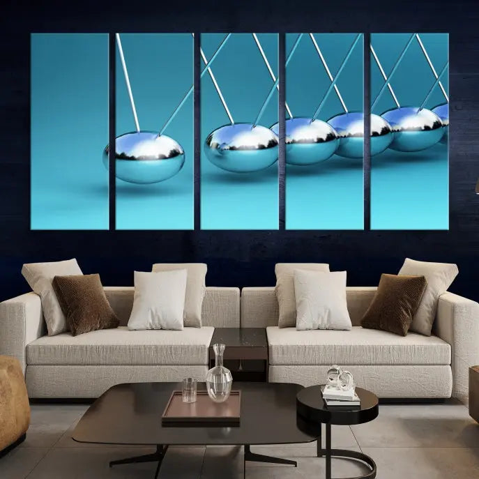 The Wall Art Newton's Cradle Canvas Print is displayed as a triptych on a teal background. Each piece is gallery-wrapped and crafted on museum-quality canvases with a UV-protective coating, ensuring lasting vibrancy and protection.