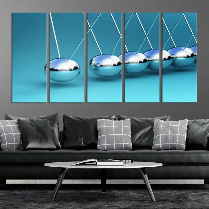 The Wall Art Newton's Cradle Canvas Print is displayed as a triptych on a teal background. Each piece is gallery-wrapped and crafted on museum-quality canvases with a UV-protective coating, ensuring lasting vibrancy and protection.