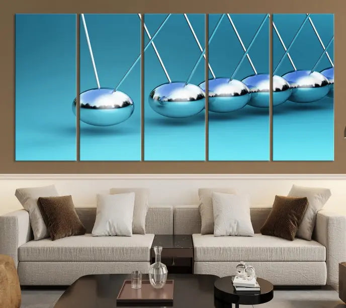 The Wall Art Newton's Cradle Canvas Print is displayed as a triptych on a teal background. Each piece is gallery-wrapped and crafted on museum-quality canvases with a UV-protective coating, ensuring lasting vibrancy and protection.