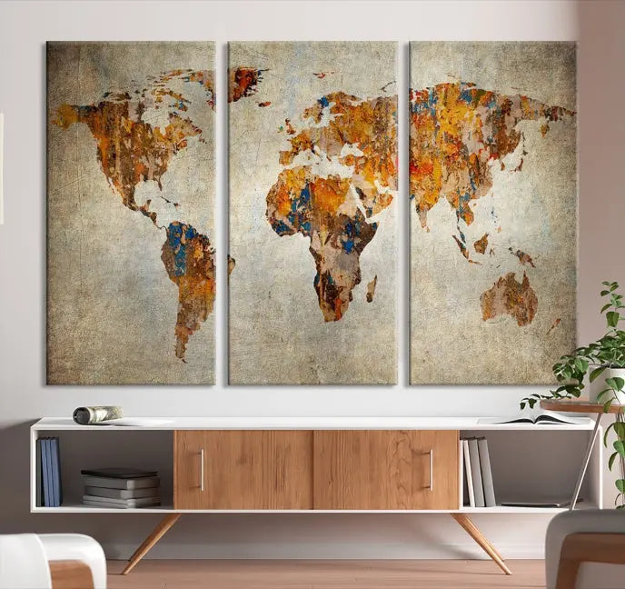 A triptych of Watercolor World Map Canvas Wall Art Prints is displayed in a dimly lit room.