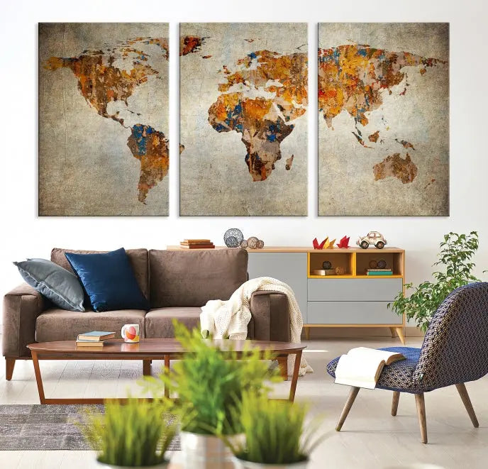 A triptych of Watercolor World Map Canvas Wall Art Prints is displayed in a dimly lit room.