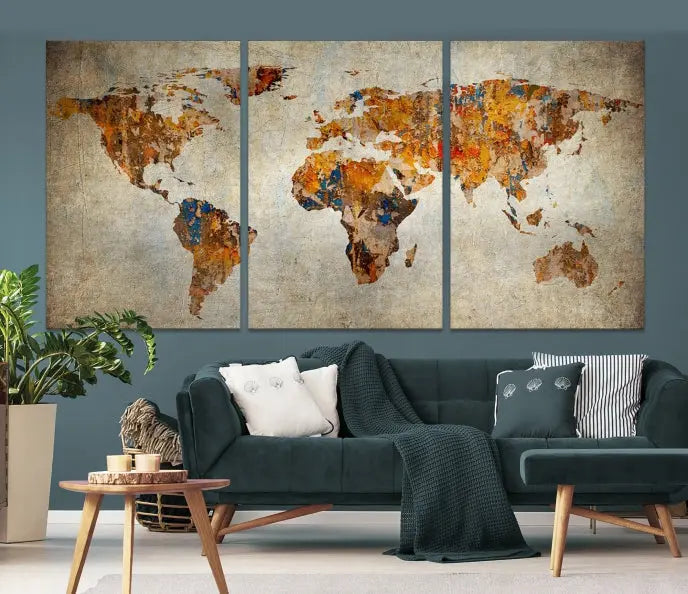 A triptych of Watercolor World Map Canvas Wall Art Prints is displayed in a dimly lit room.