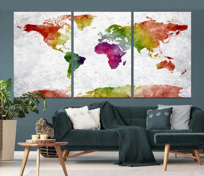 The Watercolor World Map Wall Art Canvas Print, a triptych printed on museum-quality canvases with UV-protective coating, hangs elegantly in a modern living room setting. Ready to hang, it adds an elegant touch to your space.