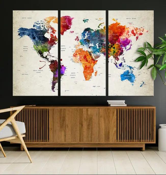 A Watercolor World Map Wall Art Canvas Print, spread across three panels, adorns a dark wall.