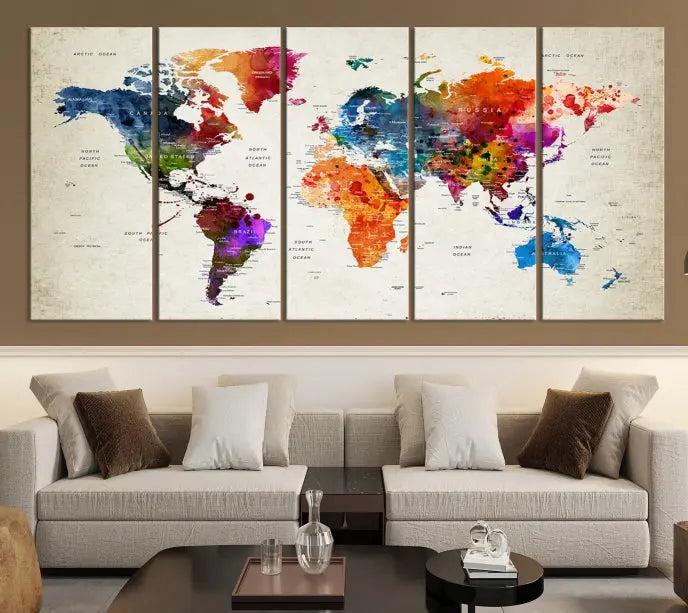 A Watercolor World Map Wall Art Canvas Print, spread across three panels, adorns a dark wall.