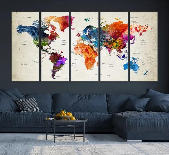 A Watercolor World Map Wall Art Canvas Print, spread across three panels, adorns a dark wall.