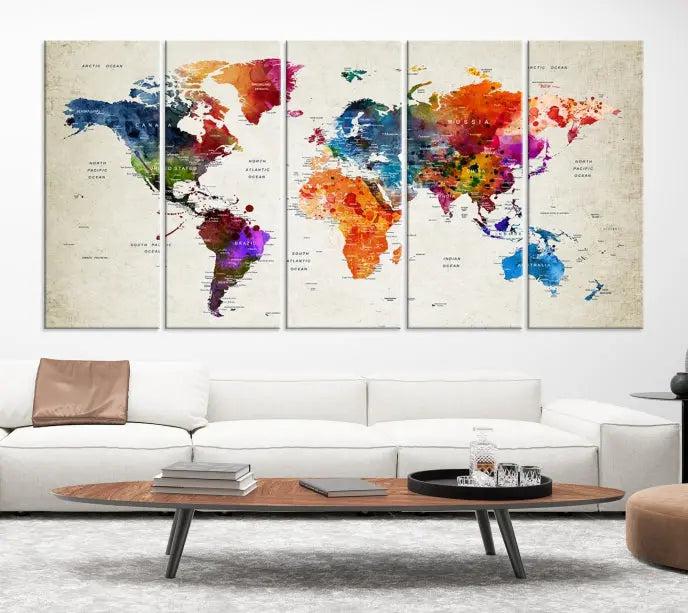 A Watercolor World Map Wall Art Canvas Print, spread across three panels, adorns a dark wall.