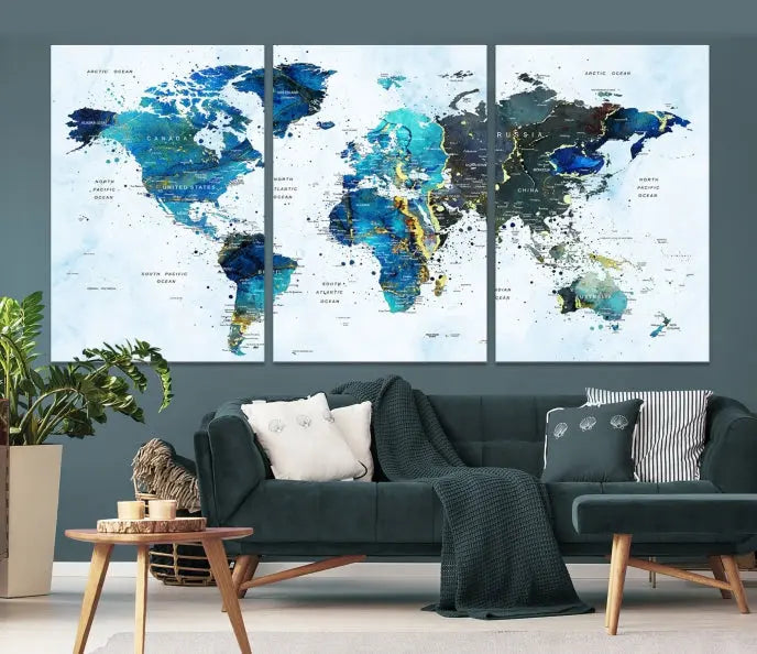 A Watercolor World Map Wall Art Canvas Print, arranged as a gallery-wrapped triptych in soothing blue and green tones, is displayed prominently.