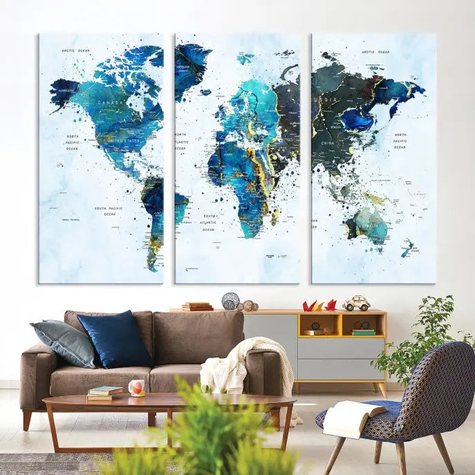 A Watercolor World Map Wall Art Canvas Print, arranged as a gallery-wrapped triptych in soothing blue and green tones, is displayed prominently.