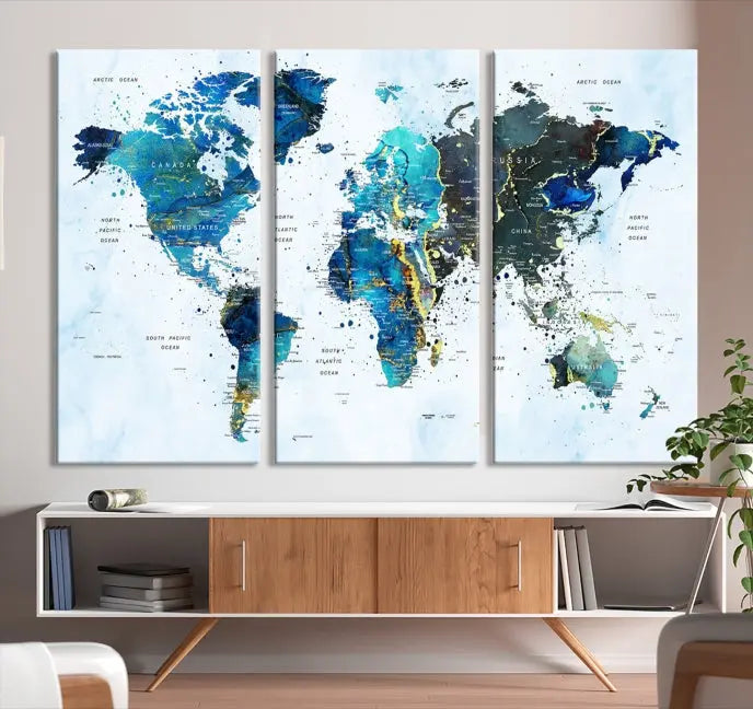 A Watercolor World Map Wall Art Canvas Print, arranged as a gallery-wrapped triptych in soothing blue and green tones, is displayed prominently.