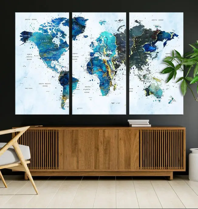 A Watercolor World Map Wall Art Canvas Print, arranged as a gallery-wrapped triptych in soothing blue and green tones, is displayed prominently.