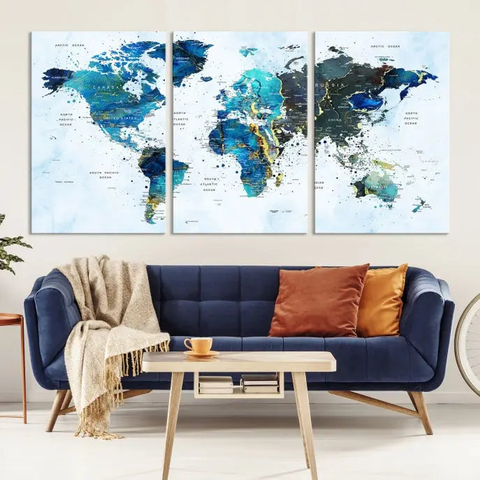 A Watercolor World Map Wall Art Canvas Print, arranged as a gallery-wrapped triptych in soothing blue and green tones, is displayed prominently.