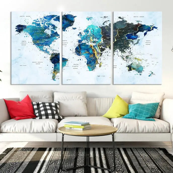 A Watercolor World Map Wall Art Canvas Print, arranged as a gallery-wrapped triptych in soothing blue and green tones, is displayed prominently.