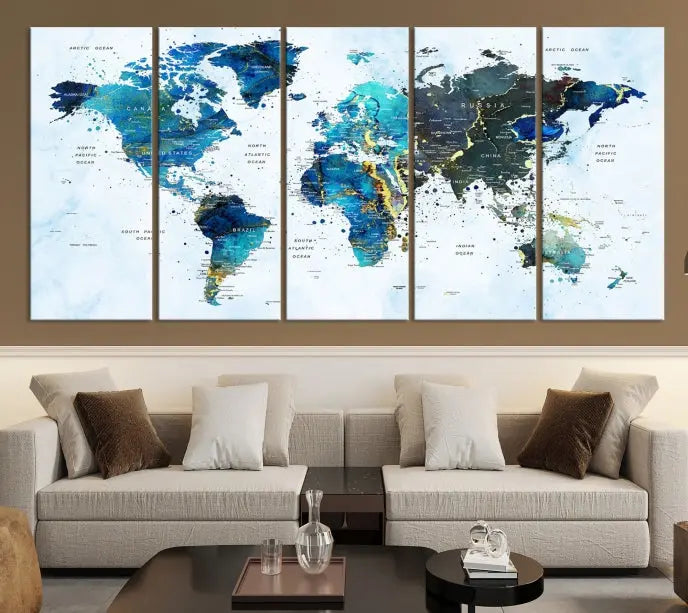 A Watercolor World Map Wall Art Canvas Print, arranged as a gallery-wrapped triptych in soothing blue and green tones, is displayed prominently.