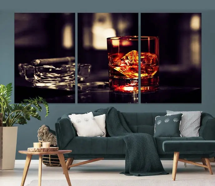 The Whiskey and Cigar Canvas, a luxurious triptych wall art for your living room or bar, portrays a whiskey glass and cigar on a table. This artwork beautifully captures the essence of opulent home decor.