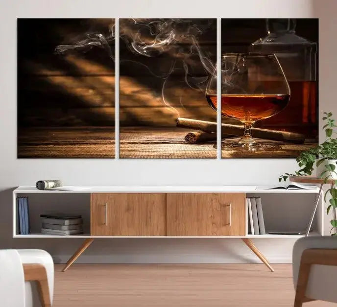 Whiskey and Cigar Wall Art Canvas Print showcases a glass of brandy, a lit cigar, and swirling smoke. This museum-quality canvas is ready to hang and features a UV-protective coating for enduring vibrancy.