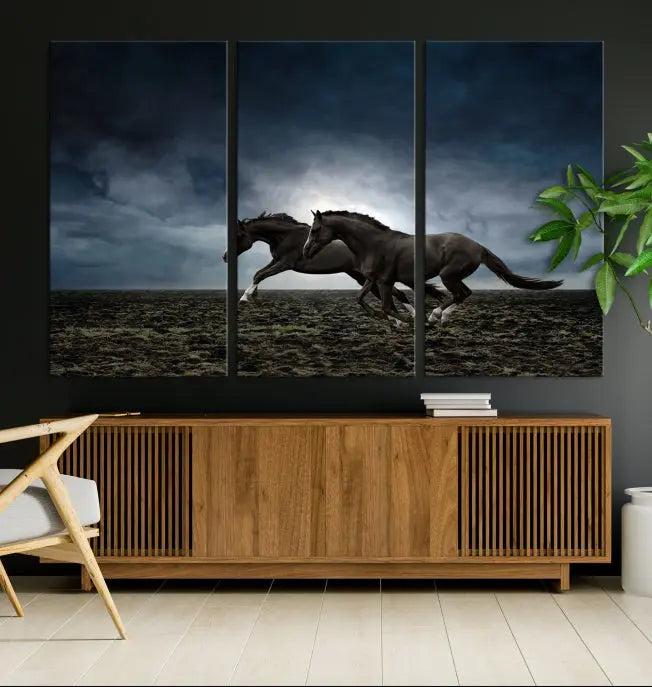 The Wild Horses Wall Art Canvas Print features a triptych of two galloping black horses set against a dark, cloudy landscape. This piece is gallery-wrapped on museum-quality canvas.