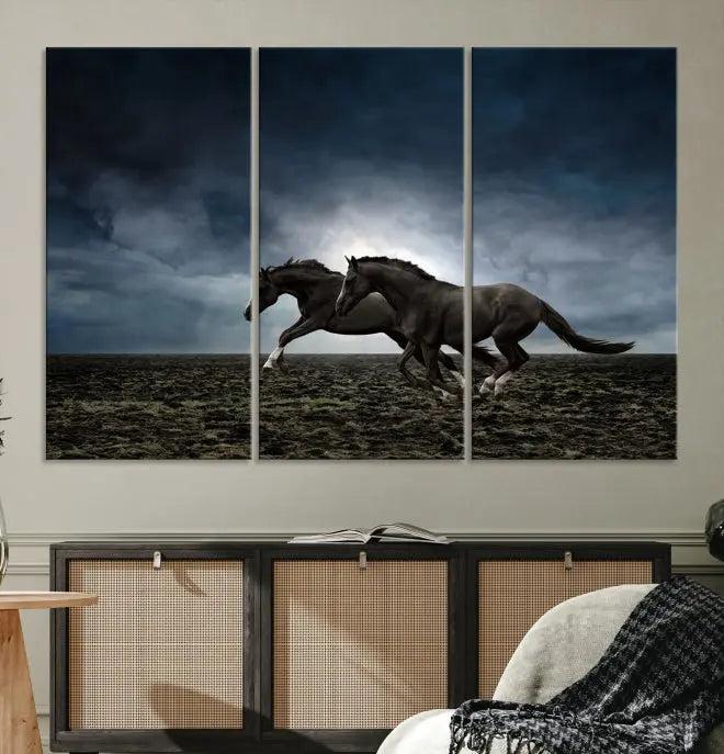 The Wild Horses Wall Art Canvas Print features a triptych of two galloping black horses set against a dark, cloudy landscape. This piece is gallery-wrapped on museum-quality canvas.