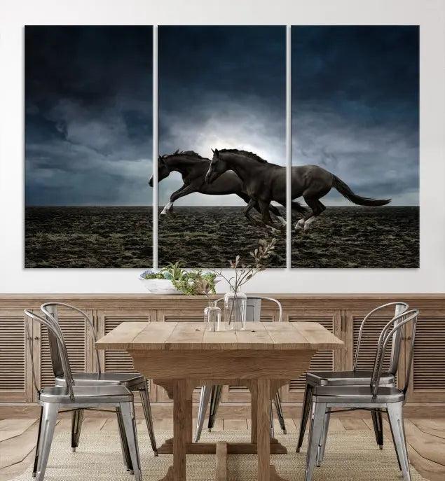 The Wild Horses Wall Art Canvas Print features a triptych of two galloping black horses set against a dark, cloudy landscape. This piece is gallery-wrapped on museum-quality canvas.