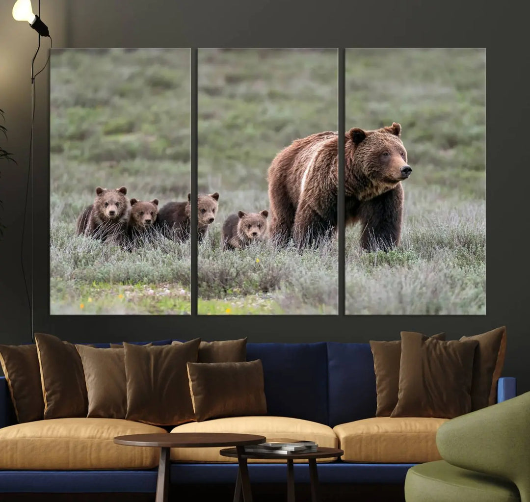 The canvas wall art print, titled "Queen of the Tetons," features a photo of 399 grizzly bear cubs walking with a larger bear in a green, open field. This striking piece is framed and leaning against a wall, showcasing its gallery-quality finish.