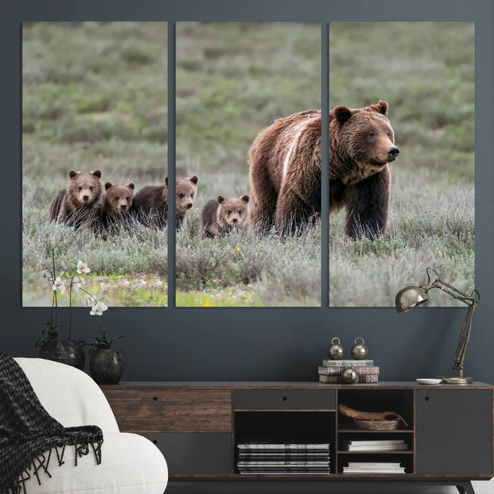 The canvas wall art print, titled "Queen of the Tetons," features a photo of 399 grizzly bear cubs walking with a larger bear in a green, open field. This striking piece is framed and leaning against a wall, showcasing its gallery-quality finish.