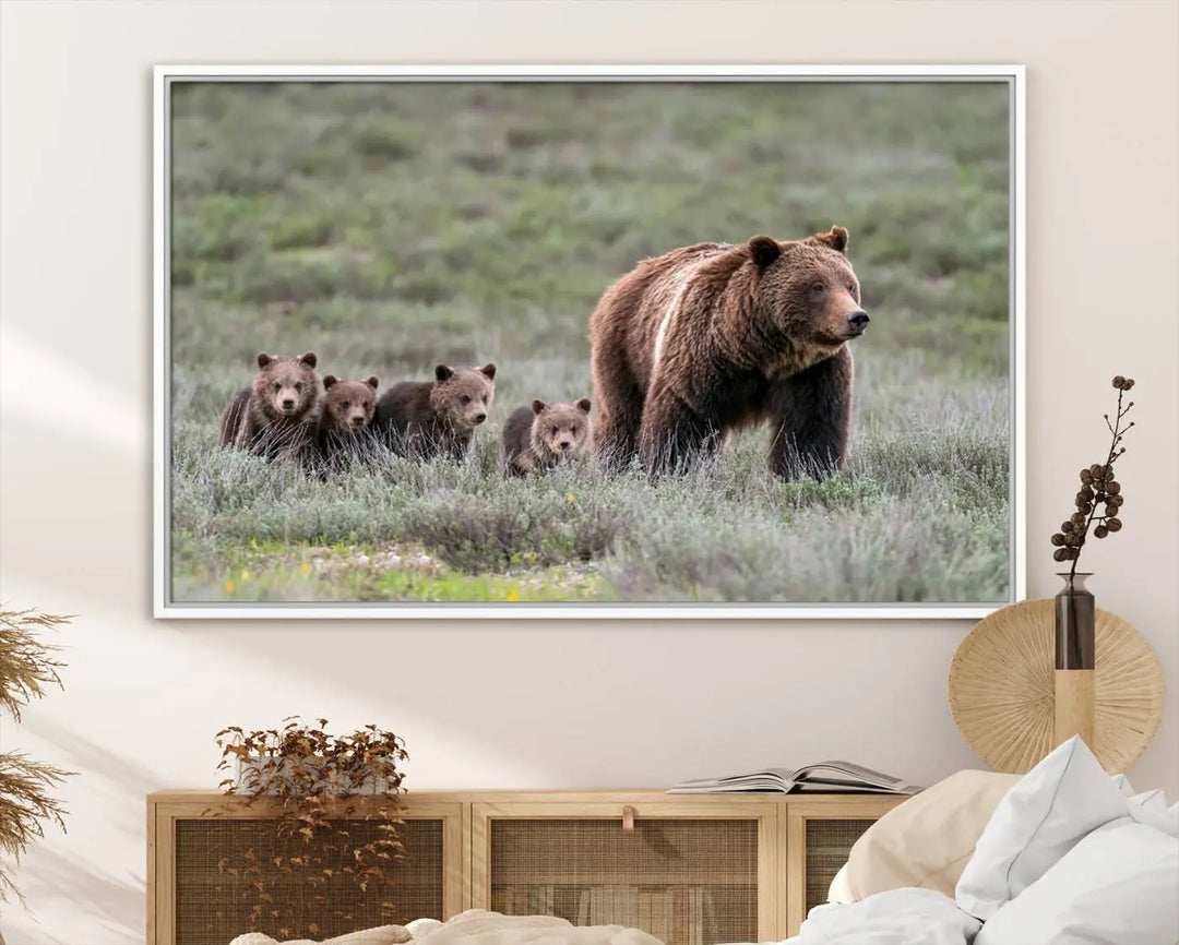 The canvas wall art print, titled "Queen of the Tetons," features a photo of 399 grizzly bear cubs walking with a larger bear in a green, open field. This striking piece is framed and leaning against a wall, showcasing its gallery-quality finish.