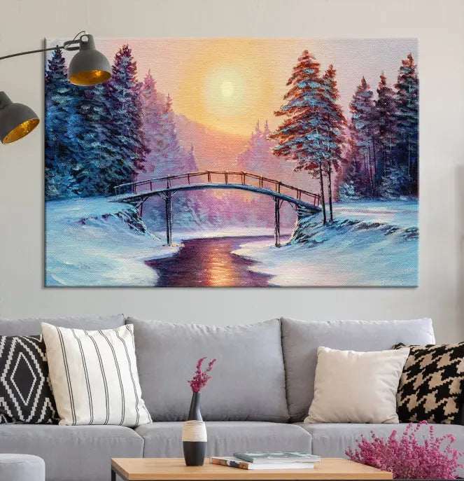 The "Winter Bridge Painting Wall Art Landscape Canvas Print" captures a serene winter landscape across three panels, showcasing a bridge, snowy trees, and a setting sun on museum-quality canvases. Each piece is gallery wrapped for an elegant finish that enhances the tranquility of the scene.