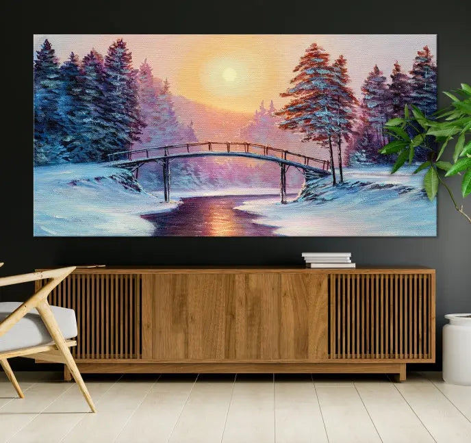 The "Winter Bridge Painting Wall Art Landscape Canvas Print" captures a serene winter landscape across three panels, showcasing a bridge, snowy trees, and a setting sun on museum-quality canvases. Each piece is gallery wrapped for an elegant finish that enhances the tranquility of the scene.