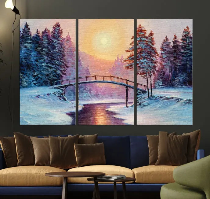 The "Winter Bridge Painting Wall Art Landscape Canvas Print" captures a serene winter landscape across three panels, showcasing a bridge, snowy trees, and a setting sun on museum-quality canvases. Each piece is gallery wrapped for an elegant finish that enhances the tranquility of the scene.