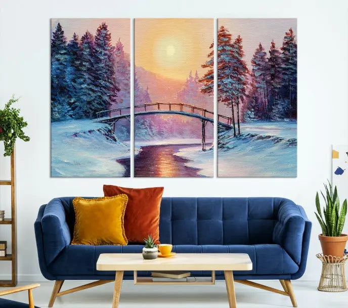 The "Winter Bridge Painting Wall Art Landscape Canvas Print" captures a serene winter landscape across three panels, showcasing a bridge, snowy trees, and a setting sun on museum-quality canvases. Each piece is gallery wrapped for an elegant finish that enhances the tranquility of the scene.