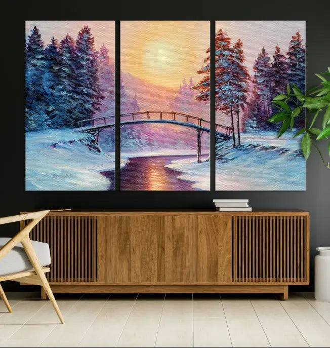 The "Winter Bridge Painting Wall Art Landscape Canvas Print" captures a serene winter landscape across three panels, showcasing a bridge, snowy trees, and a setting sun on museum-quality canvases. Each piece is gallery wrapped for an elegant finish that enhances the tranquility of the scene.