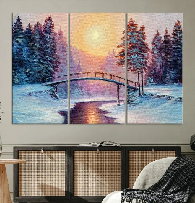 The "Winter Bridge Painting Wall Art Landscape Canvas Print" captures a serene winter landscape across three panels, showcasing a bridge, snowy trees, and a setting sun on museum-quality canvases. Each piece is gallery wrapped for an elegant finish that enhances the tranquility of the scene.