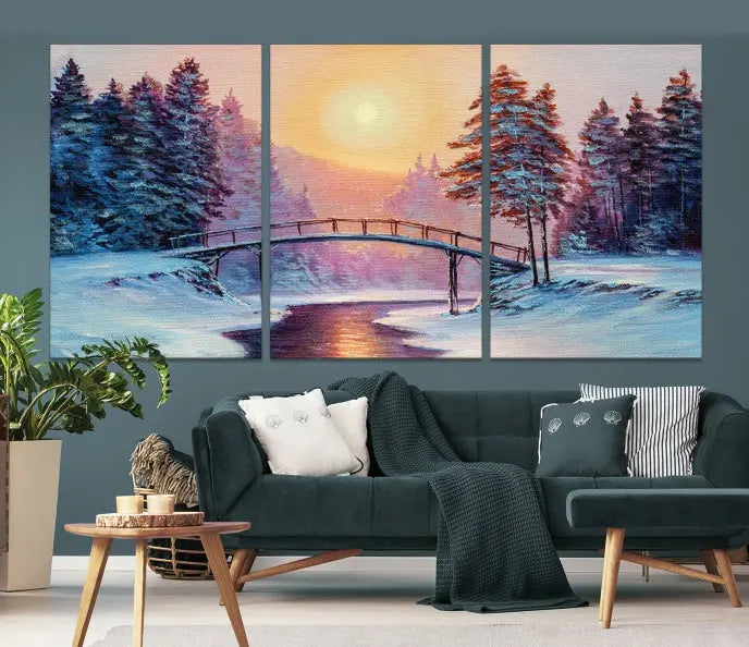 The "Winter Bridge Painting Wall Art Landscape Canvas Print" captures a serene winter landscape across three panels, showcasing a bridge, snowy trees, and a setting sun on museum-quality canvases. Each piece is gallery wrapped for an elegant finish that enhances the tranquility of the scene.