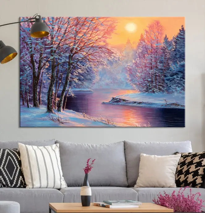 In a cozy living room, you'll find wall art titled "Winter Landscape Painting Wall Art Canvas Print," showcasing a serene snowy river scene at sunset on a museum-quality canvas with gallery-wrapped edges.