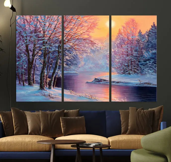 In a cozy living room, you'll find wall art titled "Winter Landscape Painting Wall Art Canvas Print," showcasing a serene snowy river scene at sunset on a museum-quality canvas with gallery-wrapped edges.