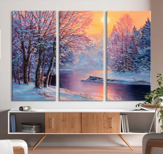 In a cozy living room, you'll find wall art titled "Winter Landscape Painting Wall Art Canvas Print," showcasing a serene snowy river scene at sunset on a museum-quality canvas with gallery-wrapped edges.