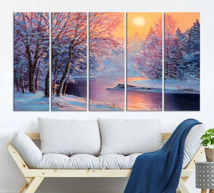 In a cozy living room, you'll find wall art titled "Winter Landscape Painting Wall Art Canvas Print," showcasing a serene snowy river scene at sunset on a museum-quality canvas with gallery-wrapped edges.