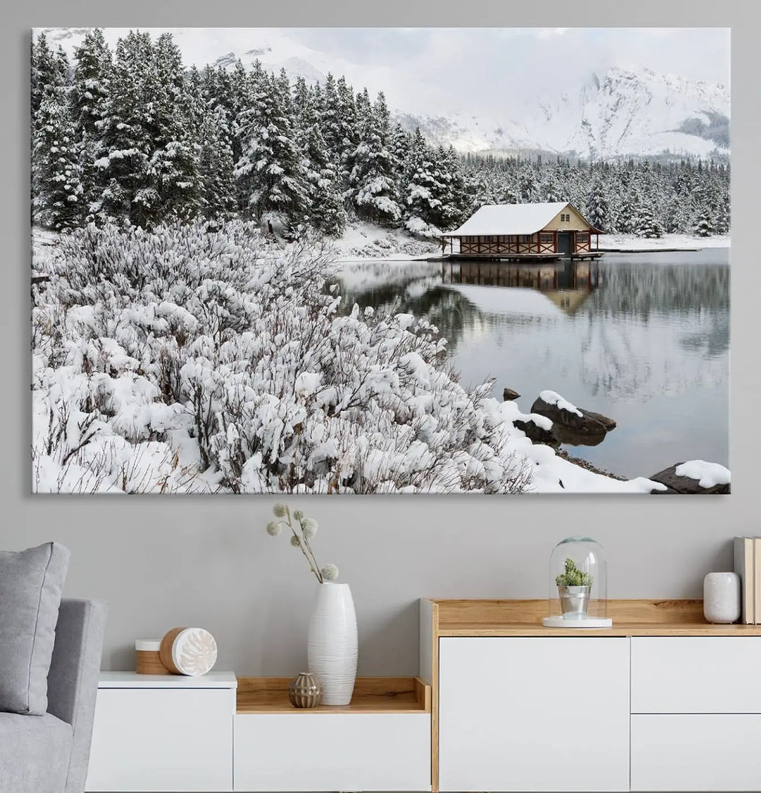 Experience the beauty of winter with the "Cabin by the Lake Canvas Wall Art," showcasing a serene snowy landscape. This rustic nature decor features a cozy cabin nestled amid snow-laden trees, set against a breathtaking mountain view, perfect for enhancing your living room.