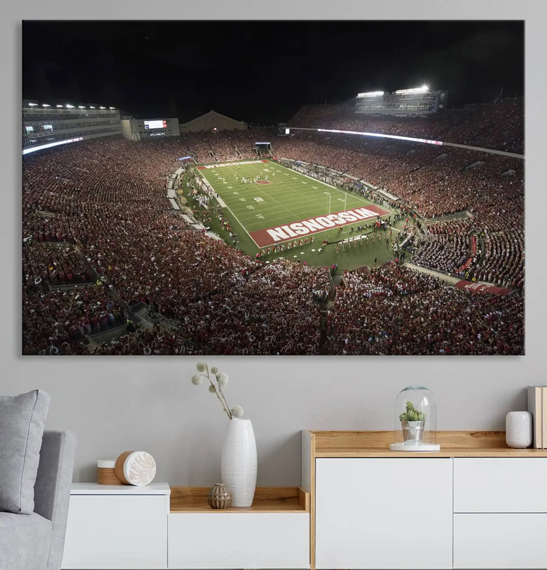 The Madison Camp Randall Stadium wall art canvas print showcases the Wisconsin Badgers football team, capturing a packed stadium at night. This three-panel piece is handmade in the USA.