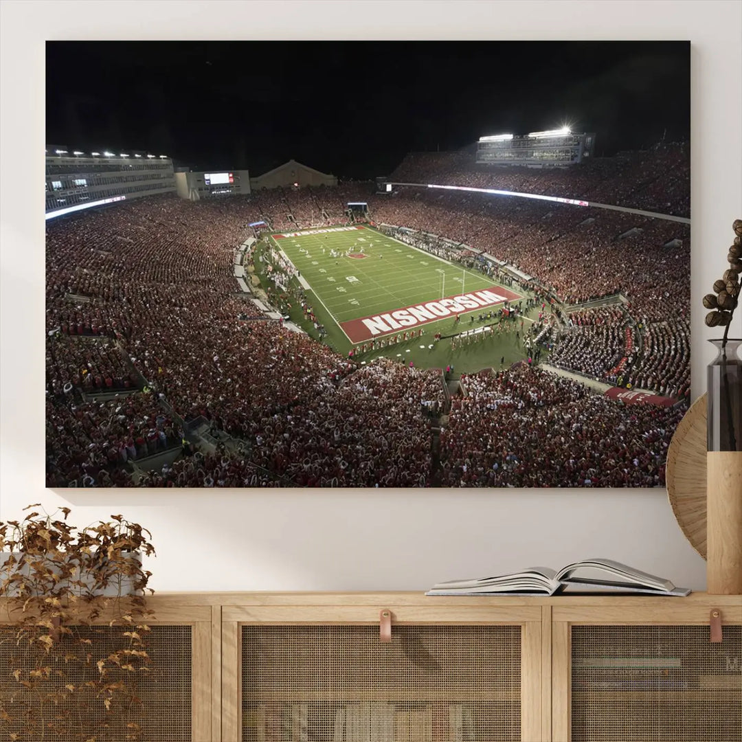 The Madison Camp Randall Stadium wall art canvas print showcases the Wisconsin Badgers football team, capturing a packed stadium at night. This three-panel piece is handmade in the USA.