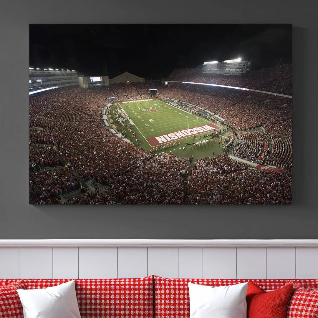 The Madison Camp Randall Stadium wall art canvas print showcases the Wisconsin Badgers football team, capturing a packed stadium at night. This three-panel piece is handmade in the USA.