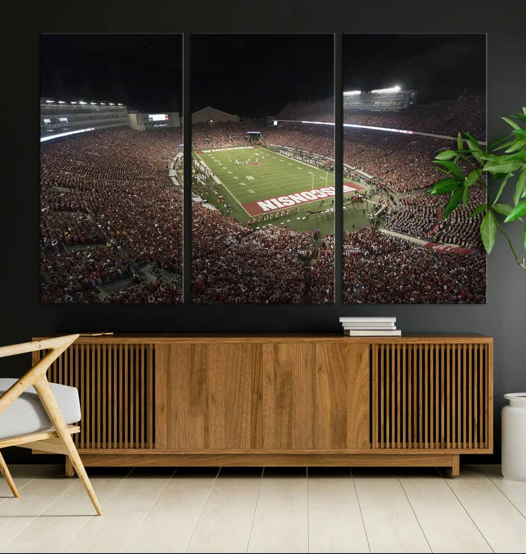 The Madison Camp Randall Stadium wall art canvas print showcases the Wisconsin Badgers football team, capturing a packed stadium at night. This three-panel piece is handmade in the USA.