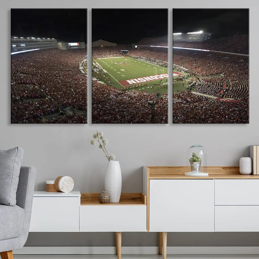 The Madison Camp Randall Stadium wall art canvas print showcases the Wisconsin Badgers football team, capturing a packed stadium at night. This three-panel piece is handmade in the USA.