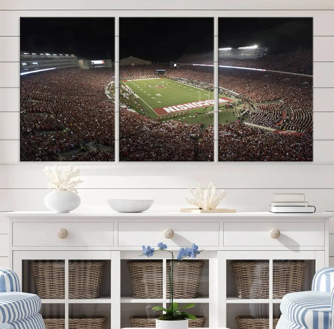 The Madison Camp Randall Stadium wall art canvas print showcases the Wisconsin Badgers football team, capturing a packed stadium at night. This three-panel piece is handmade in the USA.