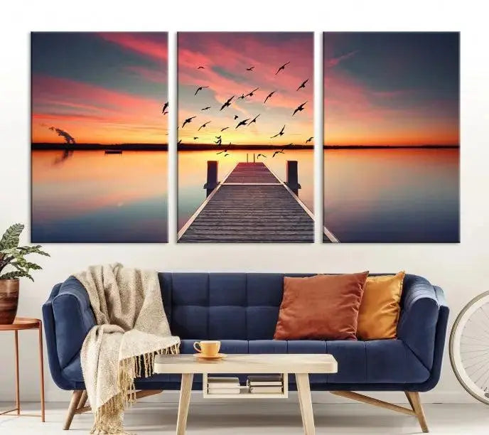 The Wood Bridge and Sunset Wall Art Canvas Print showcases a tranquil sunset scene featuring a wooden dock, soaring birds, and a vibrant sky. It comes ready to hang.