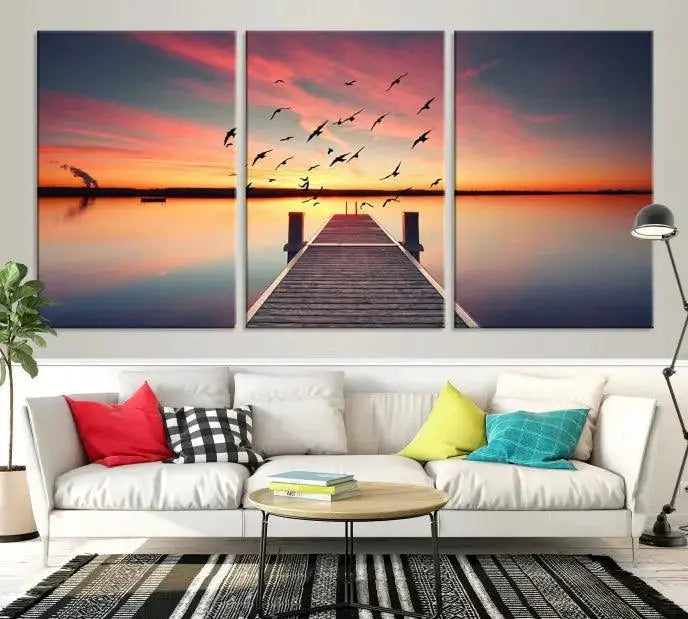 The Wood Bridge and Sunset Wall Art Canvas Print showcases a tranquil sunset scene featuring a wooden dock, soaring birds, and a vibrant sky. It comes ready to hang.