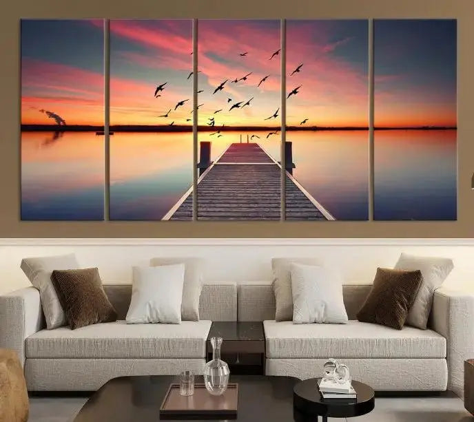 The Wood Bridge and Sunset Wall Art Canvas Print showcases a tranquil sunset scene featuring a wooden dock, soaring birds, and a vibrant sky. It comes ready to hang.