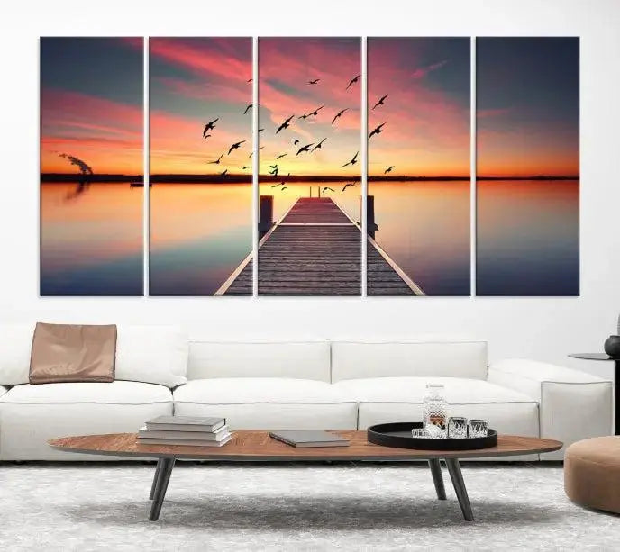 The Wood Bridge and Sunset Wall Art Canvas Print showcases a tranquil sunset scene featuring a wooden dock, soaring birds, and a vibrant sky. It comes ready to hang.