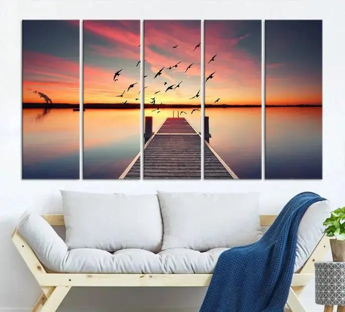 The Wood Bridge and Sunset Wall Art Canvas Print showcases a tranquil sunset scene featuring a wooden dock, soaring birds, and a vibrant sky. It comes ready to hang.