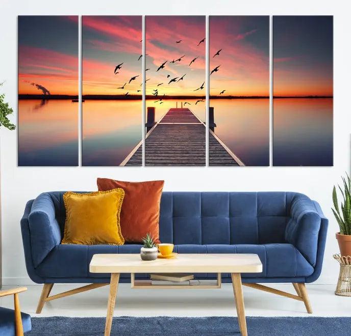 The Wood Bridge and Sunset Wall Art Canvas Print showcases a tranquil sunset scene featuring a wooden dock, soaring birds, and a vibrant sky. It comes ready to hang.